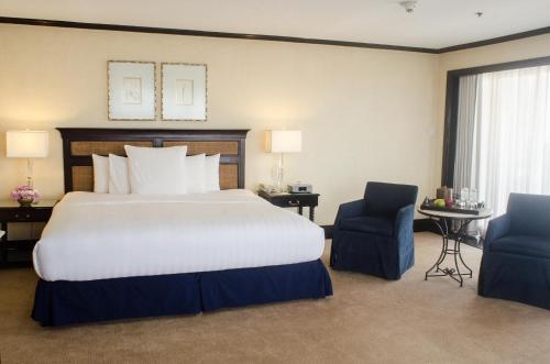 a hotel room with a large bed and two chairs at Midas Hotel and Casino in Manila