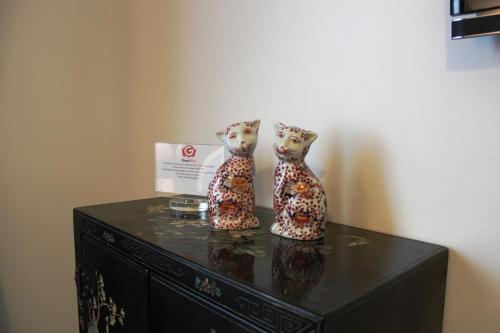 two cats figurines sitting on top of a black dresser at Résidence et Chambres d'Hôtes de La Porte d'Arras in Douai
