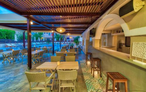 a restaurant with tables and chairs and a pool at Natalie Hotel in Laganas