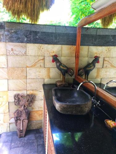a bathroom with a sink with two birds on the wall at Lullaby Bungalows in Uluwatu