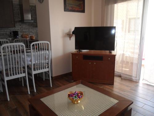 a living room with a television and a table with a bowl of candy at SUNSHINE APTS, TWO BEDROOM , FREE INTERNET, No 3 in Ayia Napa