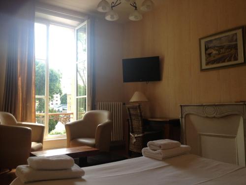 a bedroom with a bed and a tv and a window at Hotel Couleurs Sud Centre-ville Gare Charleville-Mézières in Charleville-Mézières