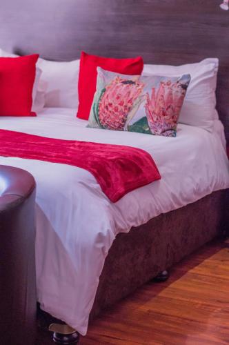 a large bed with red and white sheets and pillows at 314 on Clark Guest House in Pretoria