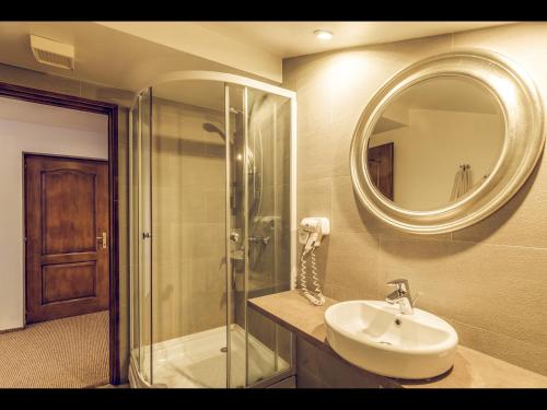een badkamer met een wastafel, een douche en een spiegel bij Pensiunea Oscar in Campina