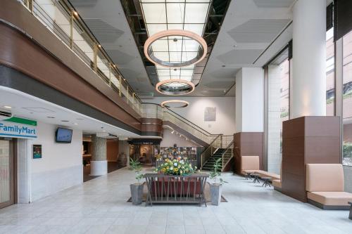 a lobby of a building with a staircase and flowers at Hotel Mystays Kagoshima Tenmonkan in Kagoshima