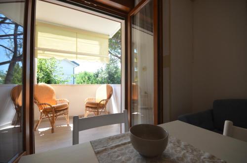 a room with a table and chairs and a glass door at Appartamenti Alisei e Cristina in Bibione