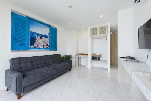 a living room with a black couch and a kitchen at Costa Village Bangsaray in Bang Sare