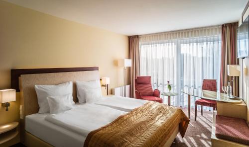 um quarto de hotel com uma cama, uma mesa e cadeiras em Best Western Plus Residenzhotel Lüneburg em Lüneburg
