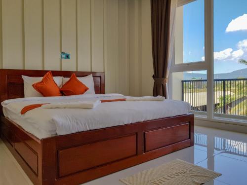 a bedroom with a bed with orange pillows and a window at Montagne Regency in Kampot