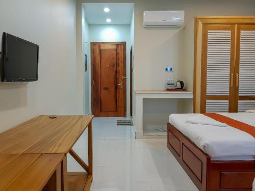 a bedroom with a bed and a desk and a television at Montagne Regency in Kampot