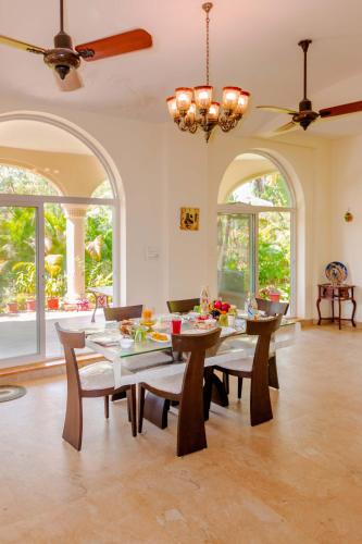 a dining room with a table and chairs and windows at SaffronStays La Casa Maestro, Kashid - spanish-style luxury villa near Kashid Beach in Kashid