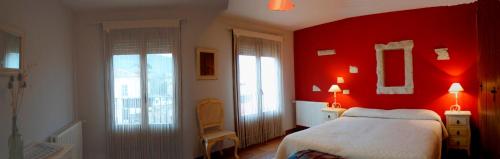 ein rotes Schlafzimmer mit einem Bett und zwei Fenstern in der Unterkunft La Noguera de Socasa in Romancos