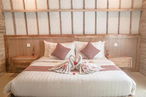a bedroom with a large bed with a bow on it at La Roja Bungalows in Nusa Penida
