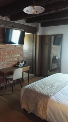 a bedroom with a bed and a desk and a tv at Agriturismo San Gallo in Strassoldo