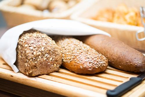 three loaves of bread and rolls on a cutting board at Hotel Orangerie in Vienna