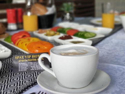 a cup of coffee sitting on a table with food at Spat Hotel Ashdod in Ashdod