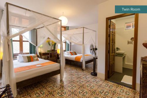 a bedroom with two beds and a mirror at The Pavilion in Phnom Penh