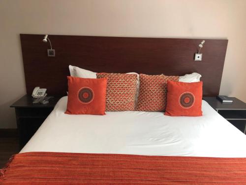 a bed with red and orange pillows on it at 314 on Clark Guest House in Pretoria