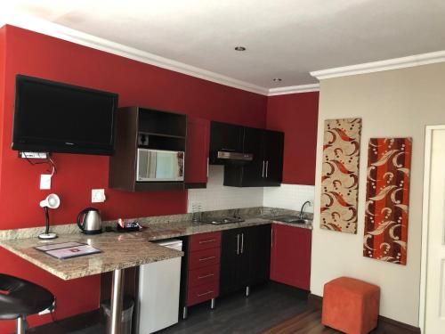 a kitchen with red walls and a counter top at 314 on Clark Guest House in Pretoria