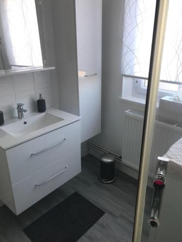 une salle de bain blanche avec un lavabo et un miroir dans l'établissement Appartement proche Mer, à Berck-sur-Mer