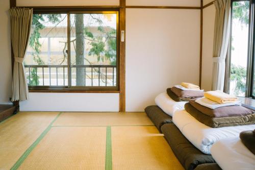two beds in a room with a large window at Onsen Guesthouse HAKONE TENT in Hakone