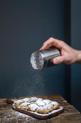 a person is sprinkling powdered sugar on a pizza at Ergon House Athens in Athens
