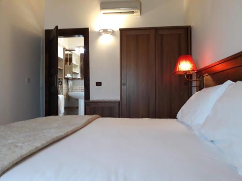 a bedroom with a large white bed and a bathroom at Agriturismo San Gallo in Strassoldo