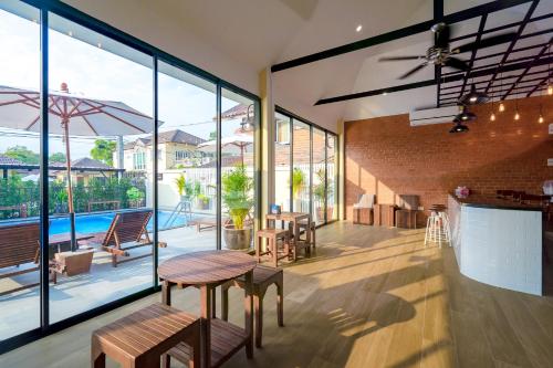 Habitación con mesas, sillas y ventanas grandes. en Suphan Lake Hometel, en Lat Krabang