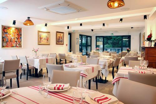 a restaurant with white tables and white chairs and tablesearcher at Logis Hotel de la Nivelle in Saint-Pée-sur-Nivelle