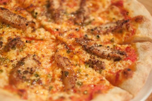 a pizza sitting on a plate on a table at Onsen Guesthouse HAKONE TENT in Hakone