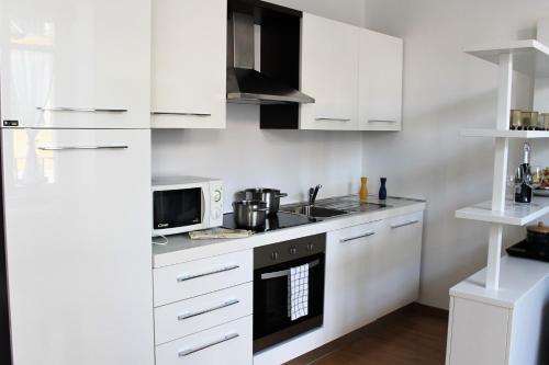 a white kitchen with white cabinets and a microwave at Perfect apartment Como in Como