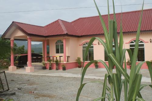 a pink building with a red roof at Malinja Home in Pantai Cenang
