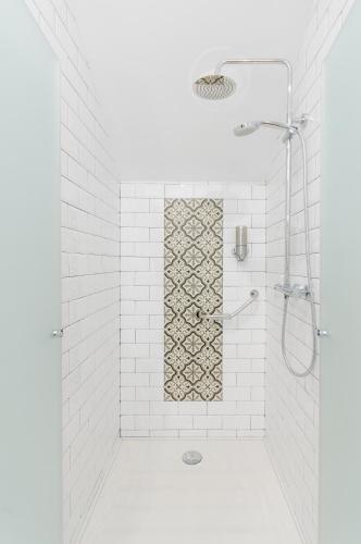 a bathroom with a shower with white tiles at Apartamentos Suites Roma in Mérida
