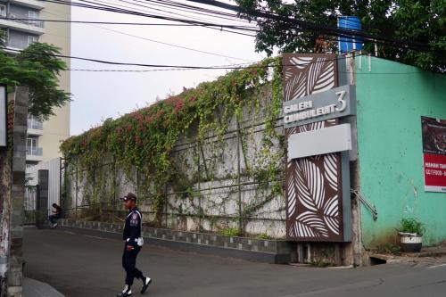 a man walking down a street next to a wall at Bacup Studio Apartment @Galeri Ciumbuleuit in Bandung