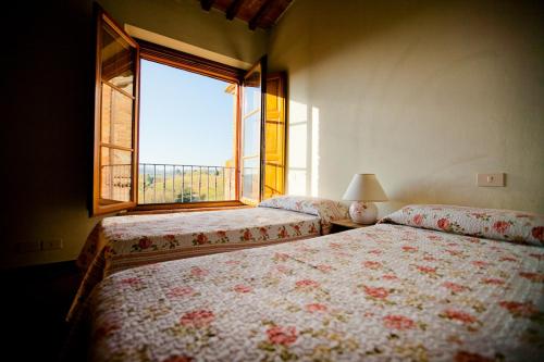a bedroom with two beds and a window at Borgo Fajani in Terricciola
