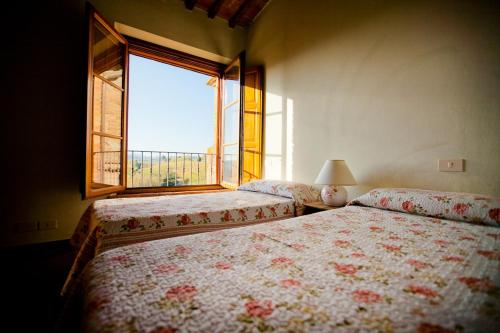 1 dormitorio con 2 camas y ventana en Borgo Fajani en Terricciola