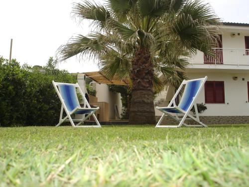 two blue chairs and a palm tree in front of a house at Villetta sul mare in Capo Vaticano