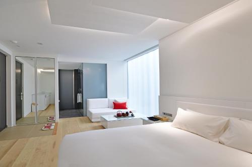 a white bedroom with a white bed and a couch at MOGANA in Kyoto