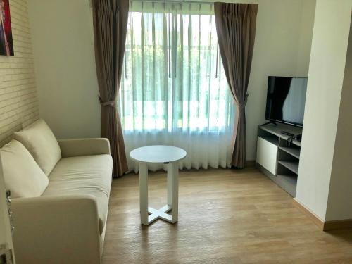 a living room with a couch and a table and a tv at The Lux Ladprao 10 in Bangkok