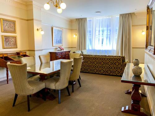 a dining room with a table and chairs and a couch at Royal Albert Hotel in Brisbane