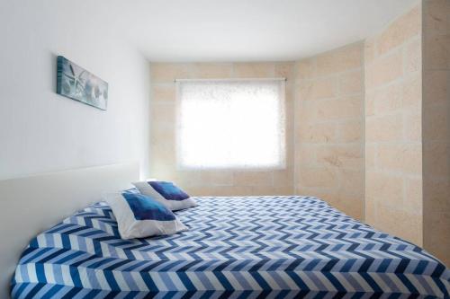 a bedroom with a blue and white bed with a window at Apartment Claveles 2 in Telde