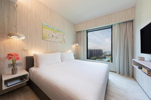 a hotel room with a large bed and a window at Village Hotel Sentosa by Far East Hospitality in Singapore
