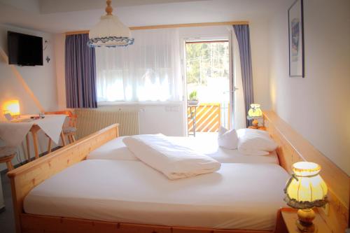a bedroom with a bed with white sheets and a window at Land-gut-Hotel Höhengasthof Adler in Lauterbach