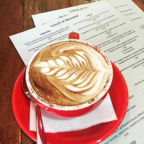 a red cup of coffee sitting on a red plate at Royal Albert Hotel in Brisbane
