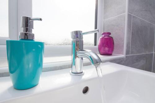 umywalkę w łazience z niebieskim dozownikiem mydła w obiekcie Foxcroft w mieście Brighouse