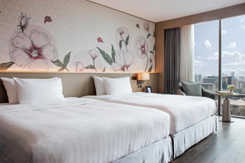 two beds in a hotel room with flowers on the wall at Sivatel Bangkok Hotel in Bangkok