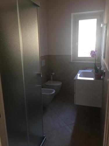 a bathroom with a toilet and a sink and a window at La Casa di Franco in Rivoli Veronese