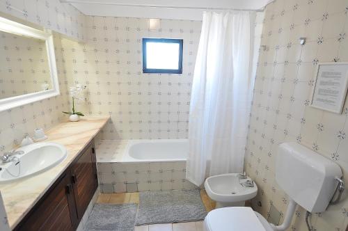 a bathroom with a tub and a toilet and a sink at E&M Beach House Aldeamento do Levante III in Porches