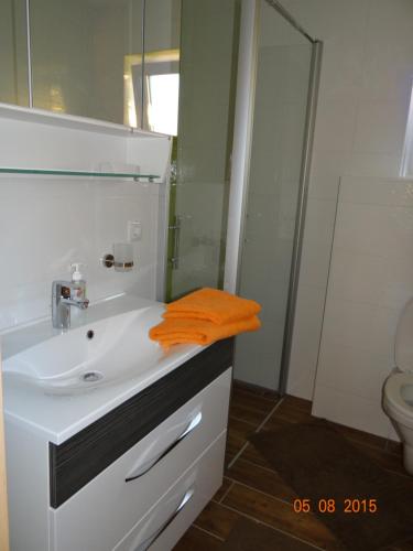 ein Badezimmer mit einem Waschbecken und einem orangenen Handtuch darauf in der Unterkunft Ferienwohnungen Resch in Eckberg