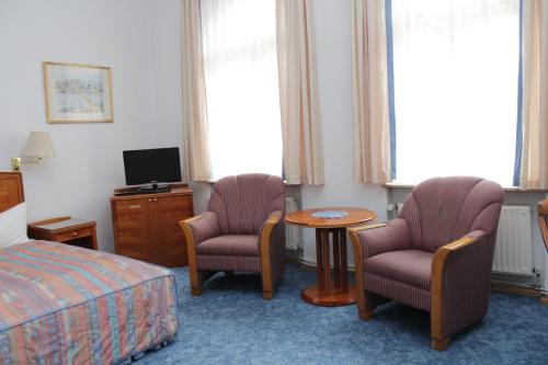 a hotel room with two chairs and a table and a bed at Weinkeller Wölk in Naumburg